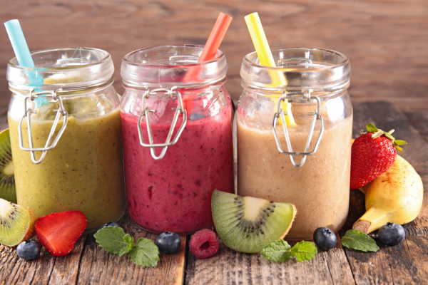Healthy fruit smoothies in glass jars with fresh strawberries, kiwi, blueberries, and raspberries